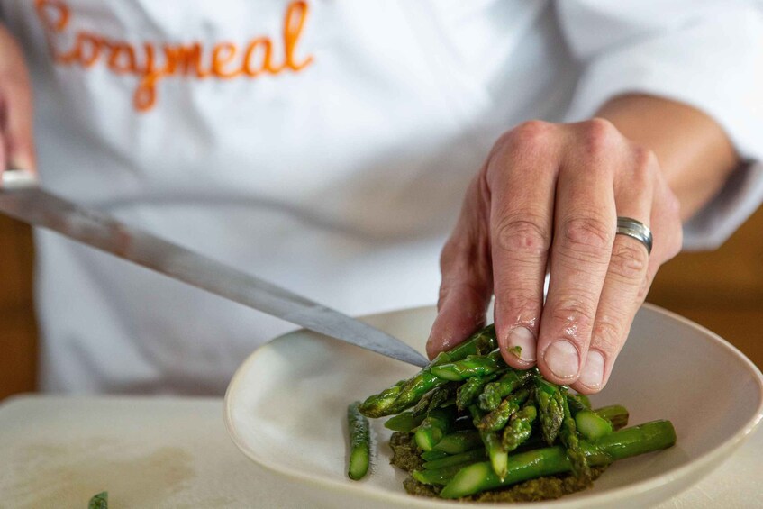 A person cutting asparagus on a plate. 2