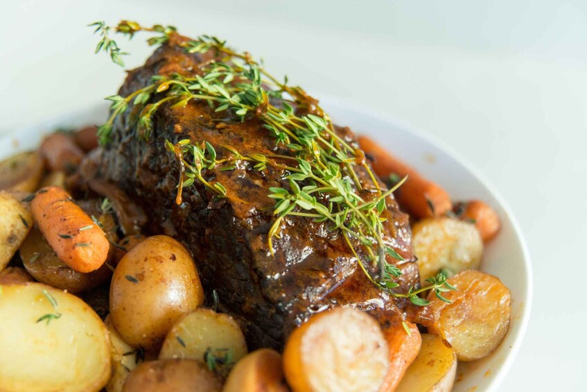 A roasted beef with carrots and potatoes garnished with thyme. 1