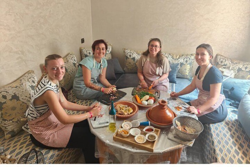 Four people sitting on a patterned sofa around a table with food and cooking utensils. 4