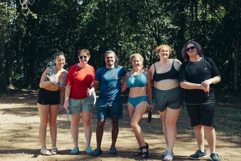 A group of people standing outdoors in a natural setting with trees in the background. 3