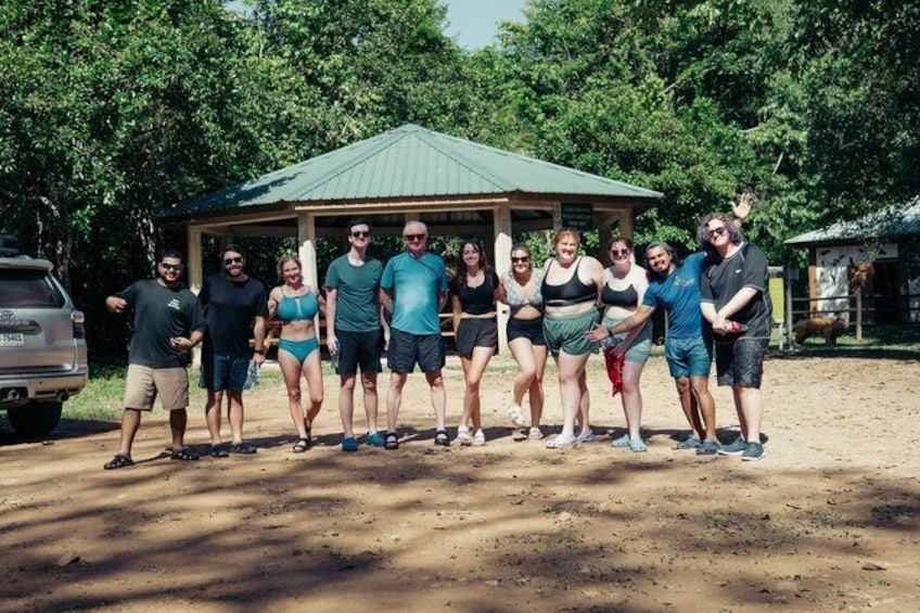 A group of people standing in a line with a gazebo in the background. 2