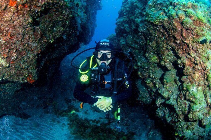 A diver in a cave with rocky walls and water. 4