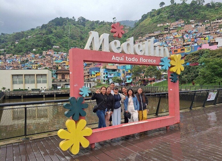 A group of people posing in front of a sign that reads 'Medellin Aqui todo florece.' 4