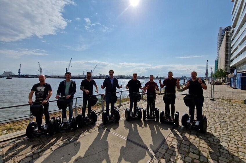 A group of people riding hoverboards along a waterfront promenade. 5