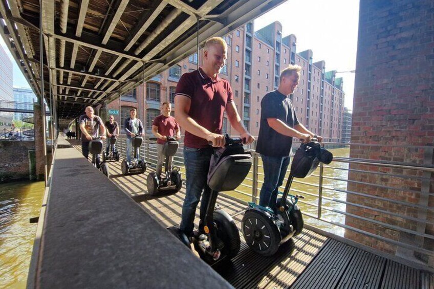 People riding Segways on a covered walkway by a river. 3