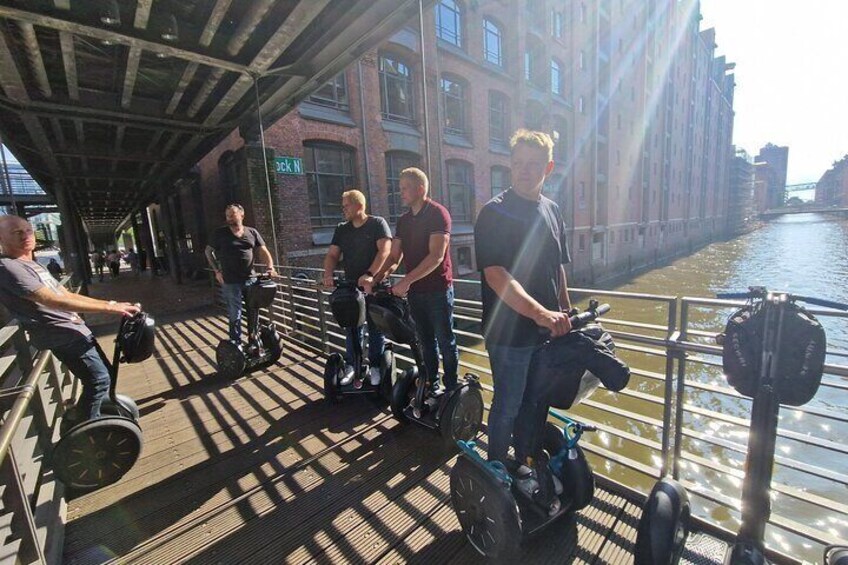 People riding Segways on a bridge over a river. 4