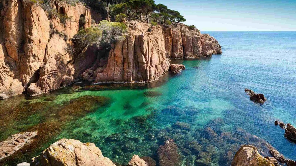 A coastal landscape with rocky cliffs and clear turquoise waters. 1