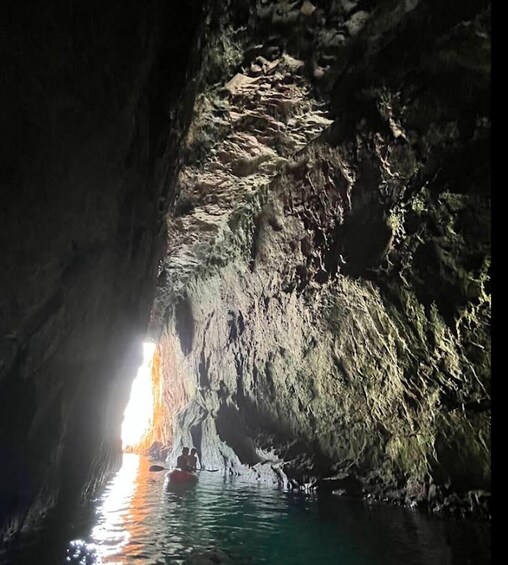 A cave with water at the bottom and sunlight streaming through the top. 2