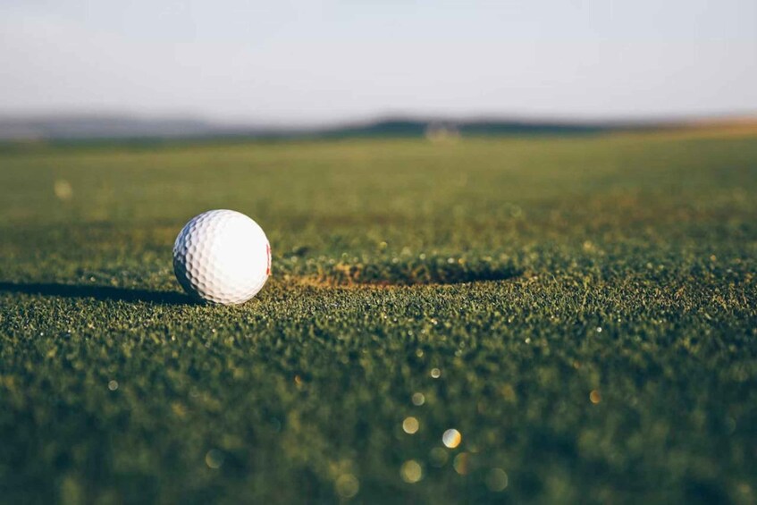 A golf ball on a green with a hole nearby. 3