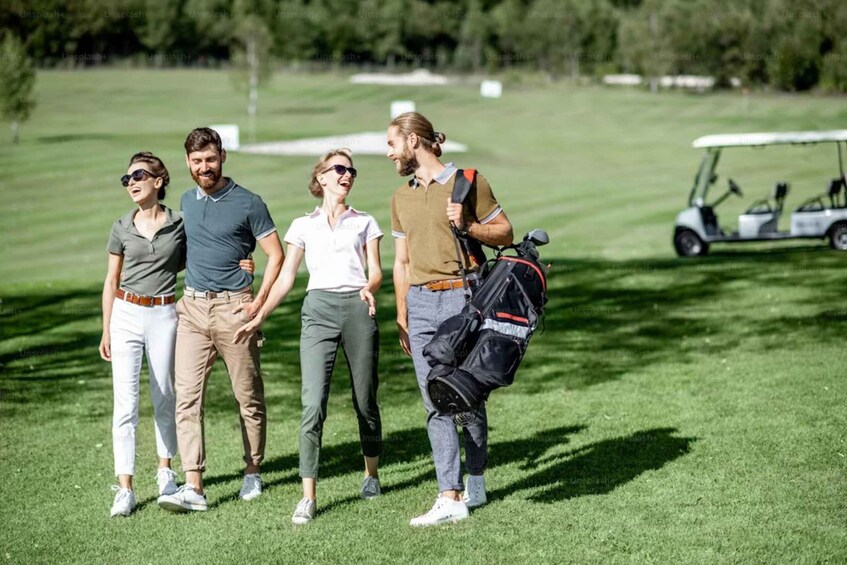 A golf course with players and a golf cart. 2