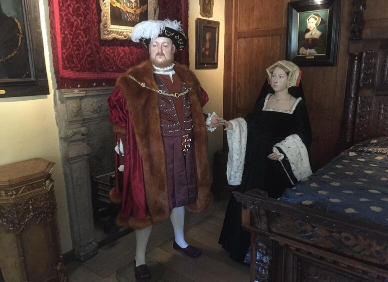 A historical room with a red patterned wall, a wooden bed, and a statue. 3