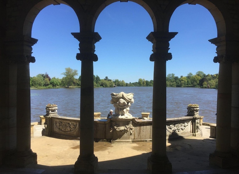 A stone pavilion with arches overlooking a calm lake. 4