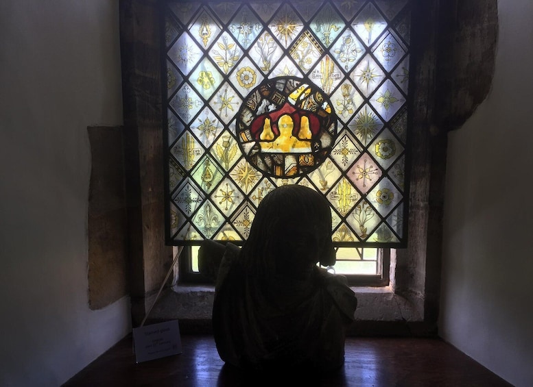 A person sitting in front of a stained glass window with geometric patterns and a central design. 2