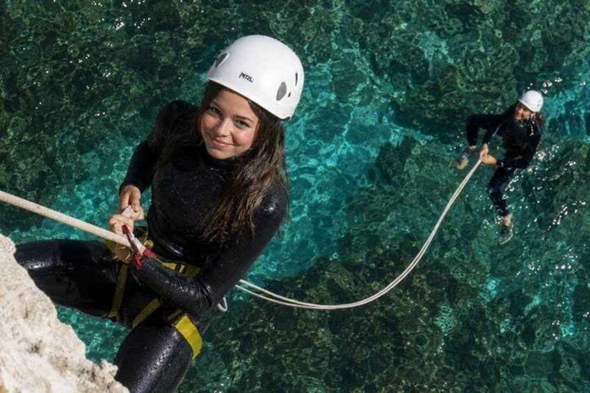 A person rappelling into clear blue water with a rope. 5