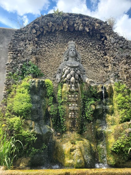 A stone statue with a waterfall in front of it. 5