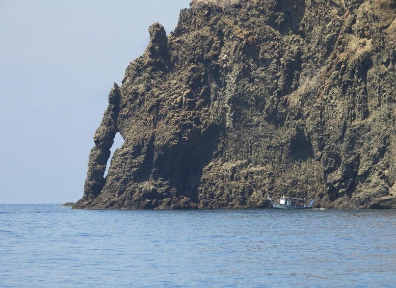 A rocky coastline with a boat anchored near the shore. 3