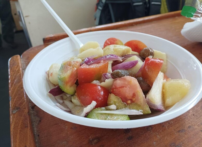A bowl of fruit salad with a white spoon on a wooden table. 5