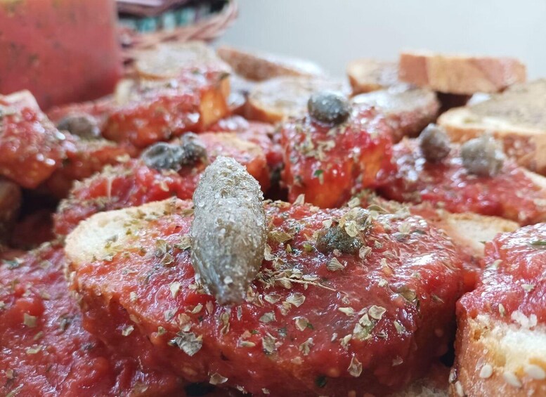 A close-up of food items, possibly bruschetta, with a tomato-based topping and herbs. 4