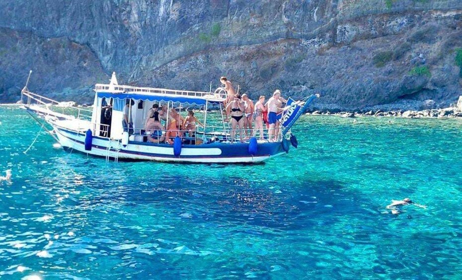 A boat with people on it in clear blue water. 1