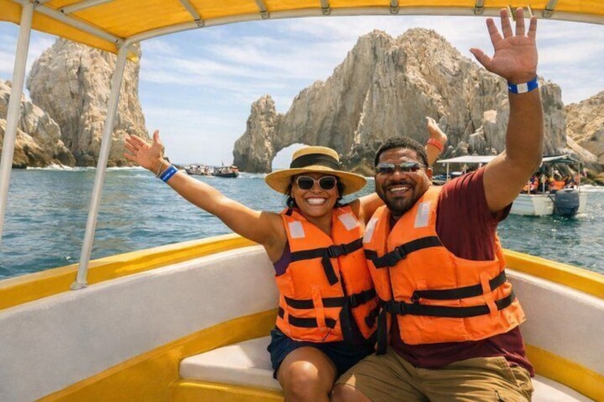 Two people on a boat with rocky cliffs in the background. 1