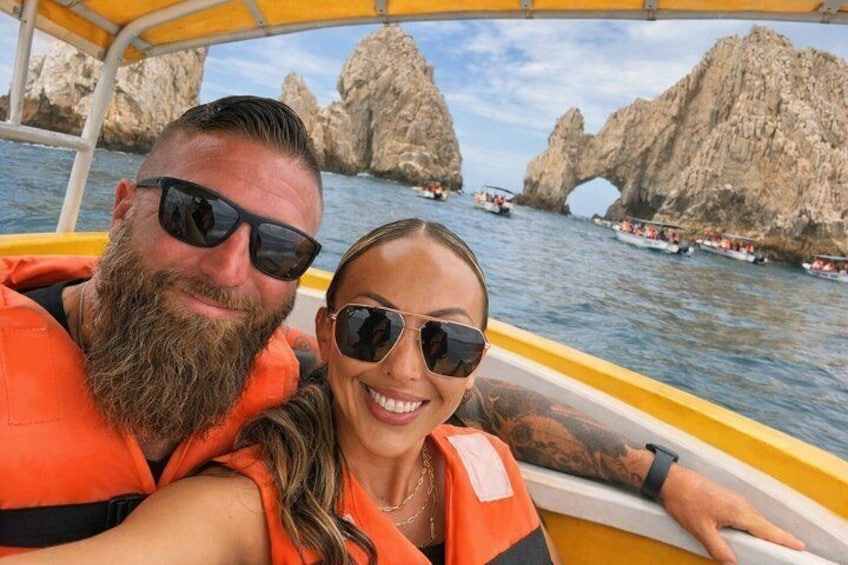 A boat with two people wearing life jackets, rocky cliffs, and a clear sky in the background. 4