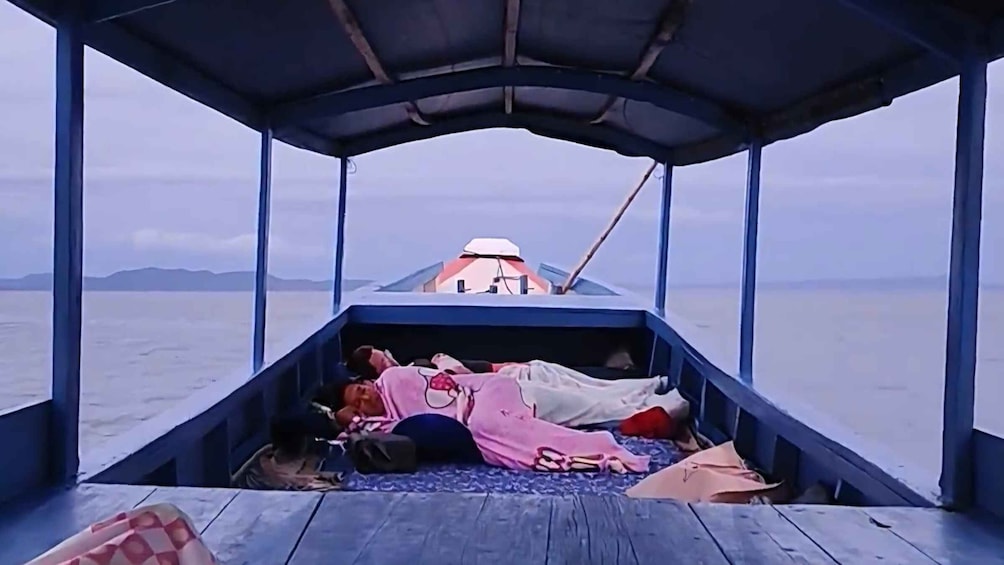 A boat with a covered deck and passengers lying down. 2