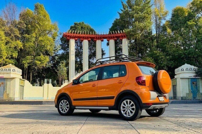 An orange car parked in front of a building with a red roof and white pillars. 2