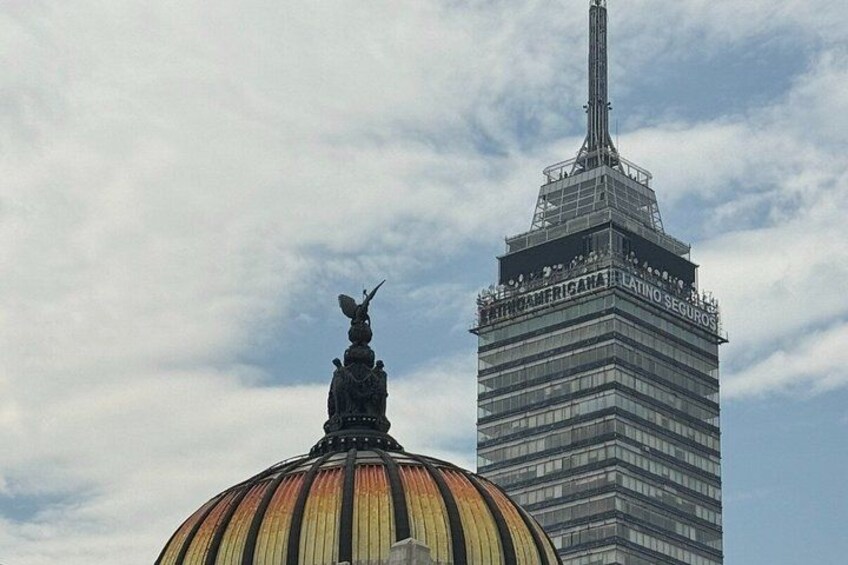A large dome with a statue on top and a tall skyscraper in the background. 1