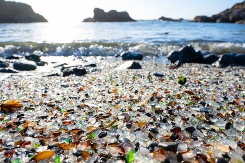A beach with a variety of colorful glass pieces scattered across the sand. 2