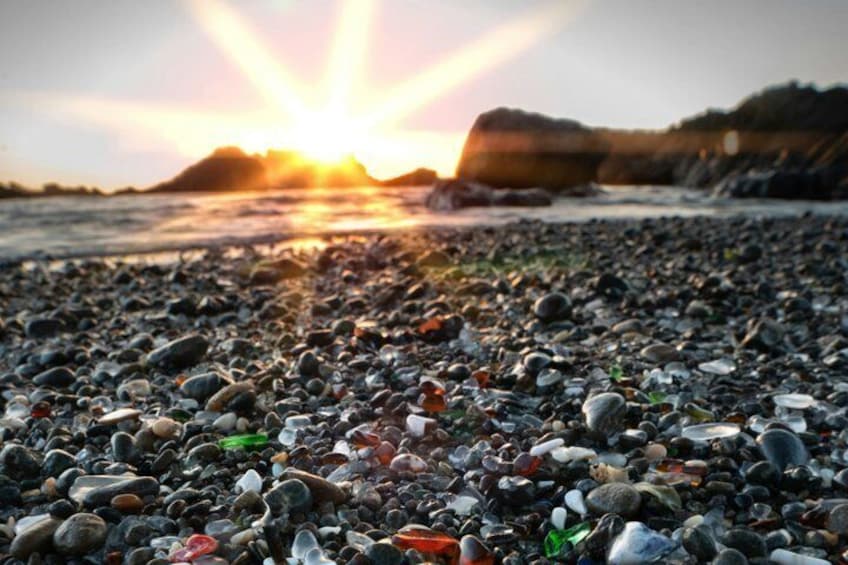 A pebble beach at sunset with the sun low on the horizon. 3