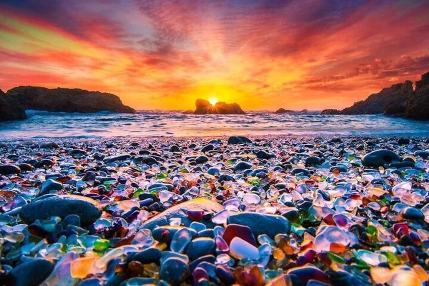 A beach with colorful glass bottles and a sunset over the ocean. 1