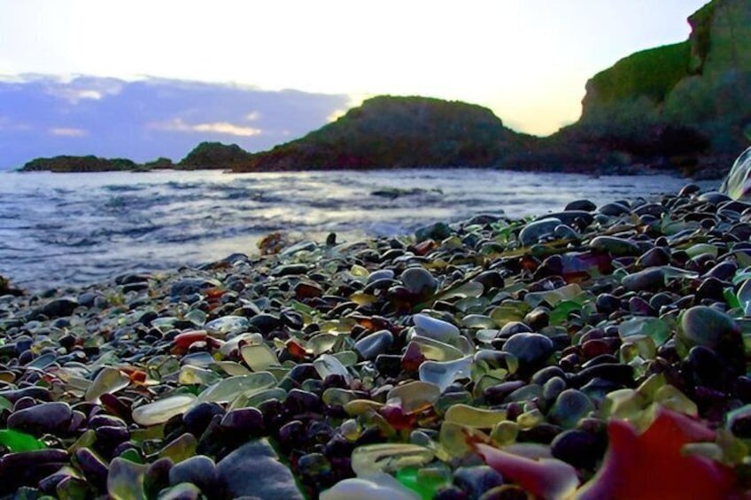 A pebble beach with colorful glass pieces and a rocky coastline. 4