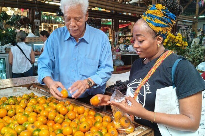 A fruit market with oranges and a person examining them. 1