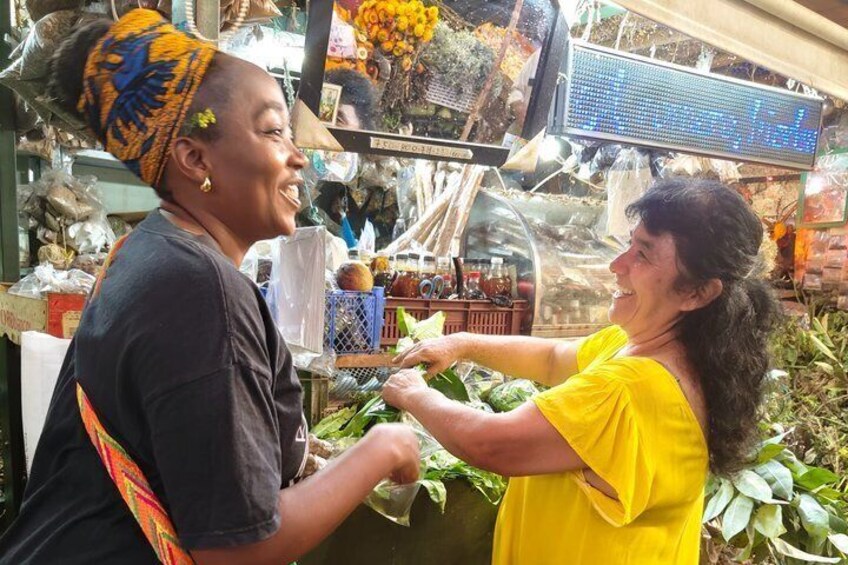 Two people at a market stall with various goods on display. 5