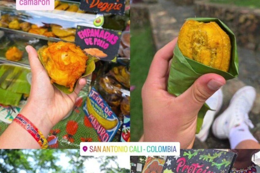A person holding a food item wrapped in a leaf, with a sign indicating 'Empanadas de Pudo' and 'Tortas de Mango' in the background. 4