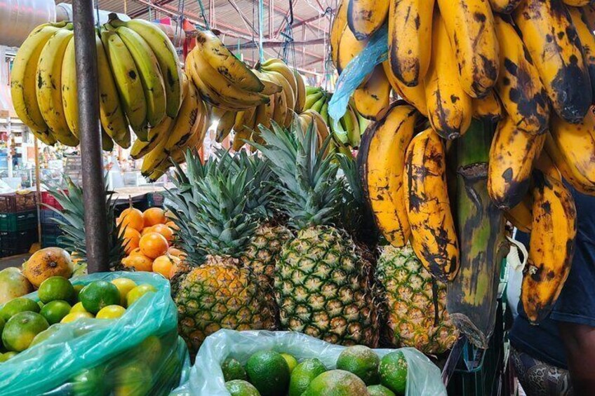 A market stall with bananas, pineapples, and limes. 4