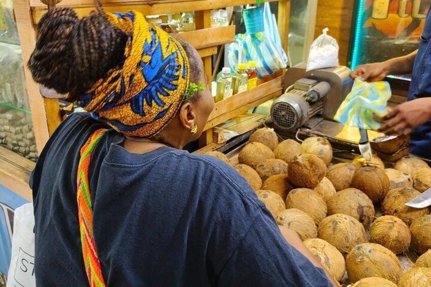 A person at a food stall with coconuts and a motorized grater. 3