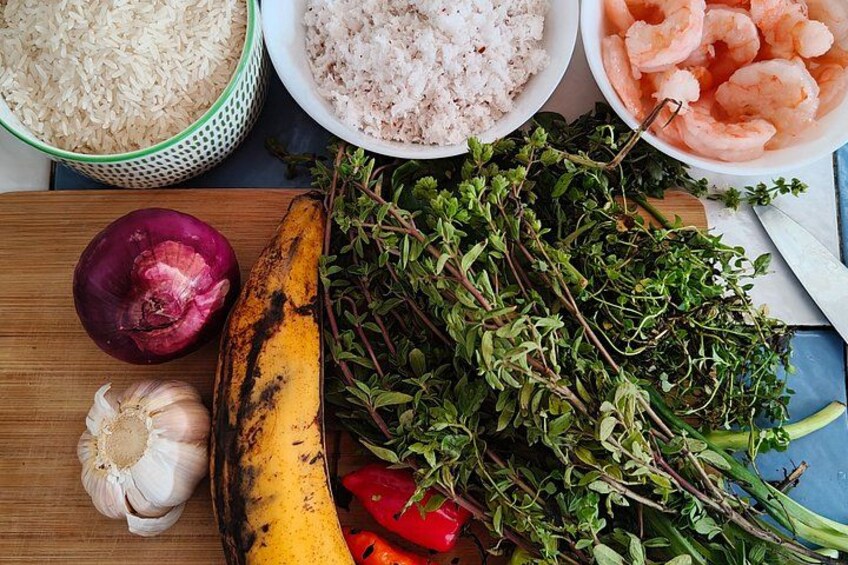 A variety of fresh ingredients including rice, shrimp, a banana, an onion, garlic, and herbs on a wooden surface. 3