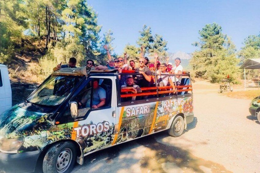 A safari vehicle with passengers, surrounded by trees and a clear sky. 4
