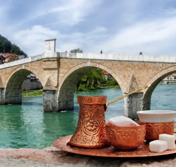 A stone bridge over water with copper vessels and a spoon. 5