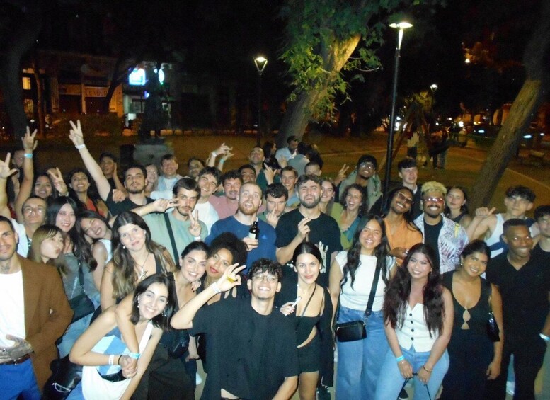 A nighttime outdoor gathering of people with trees and street lamps in the background. 1