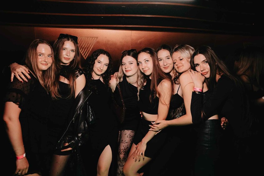 A group of people in a dimly lit indoor setting, possibly a club or event space. 2