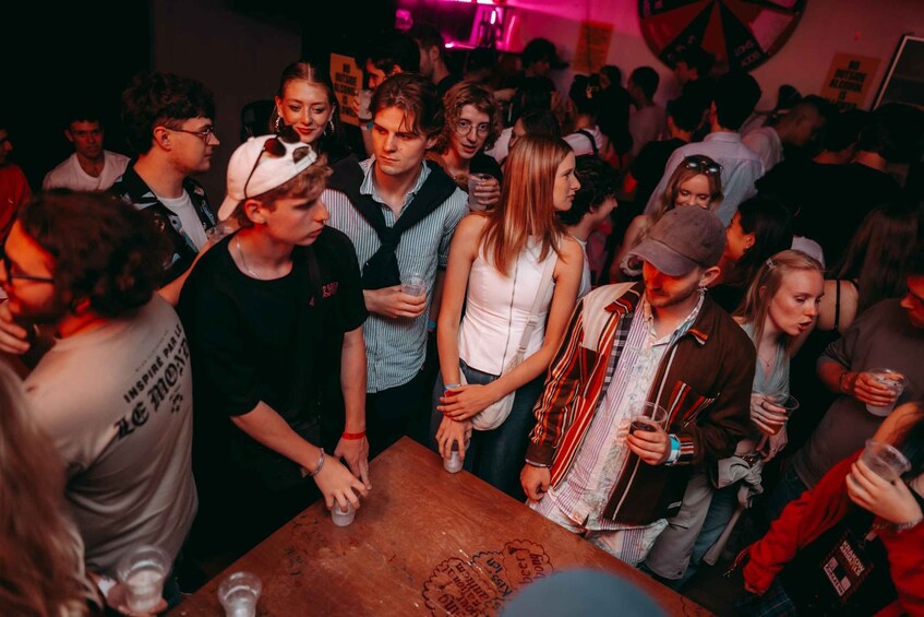 A crowded indoor social event with people standing around tables. 4