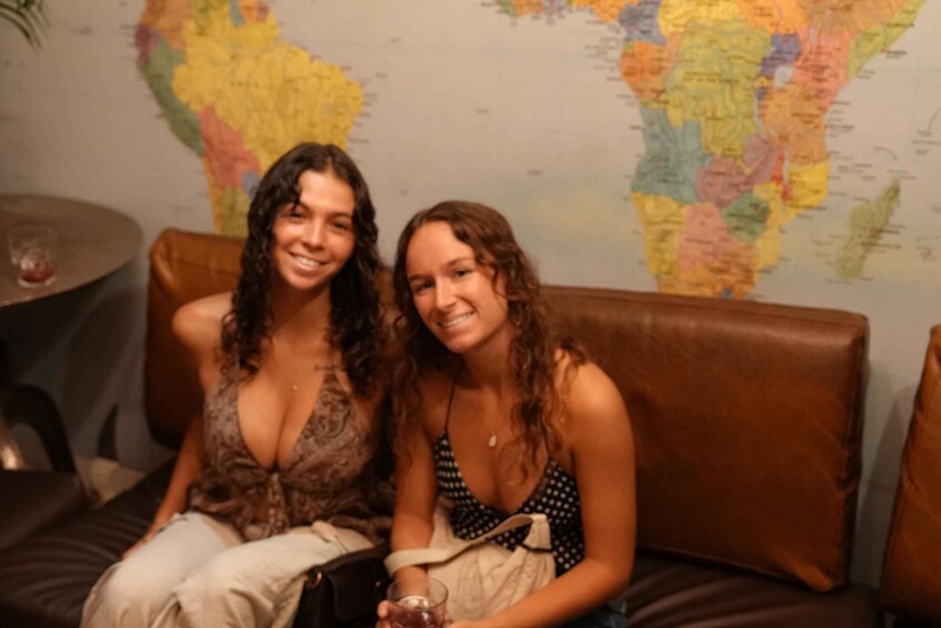 Two people sitting on a couch with a world map in the background. 2