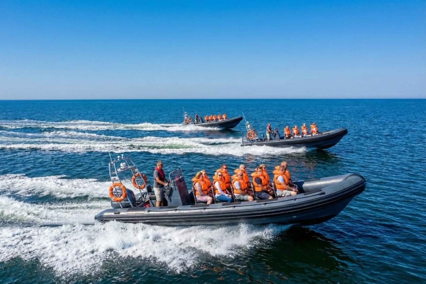 Two motorboats on a calm sea with passengers wearing life jackets. 1