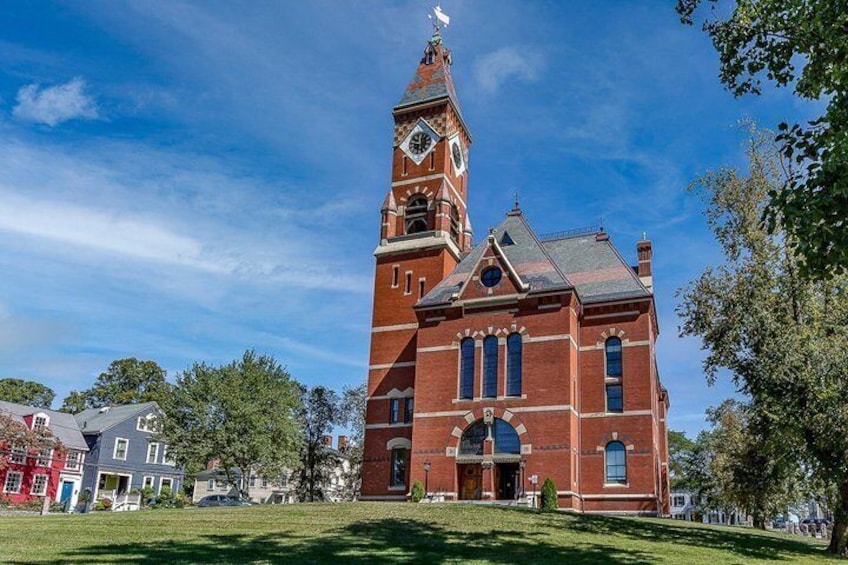 A red brick church with a clock tower and a lawn in front. 5
