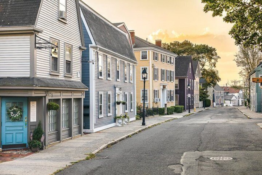 A quiet street lined with colorful houses, a clear sky, and a man walking down the road. 2
