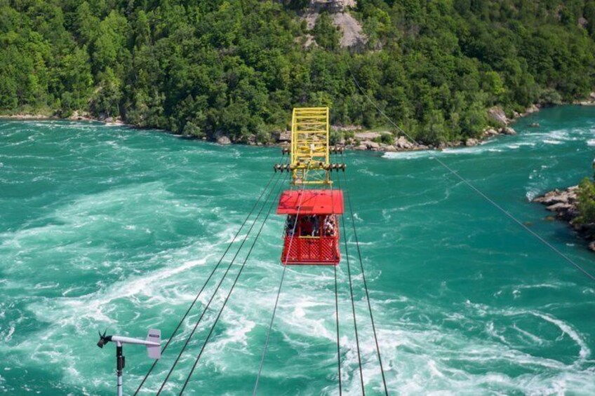 A cable car system over a river with a forested area in the background. 4