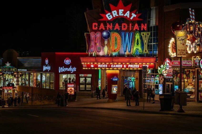 A brightly lit entertainment venue with neon signs, including 'Great Canadian' and 'Wendy's' visible. 2
