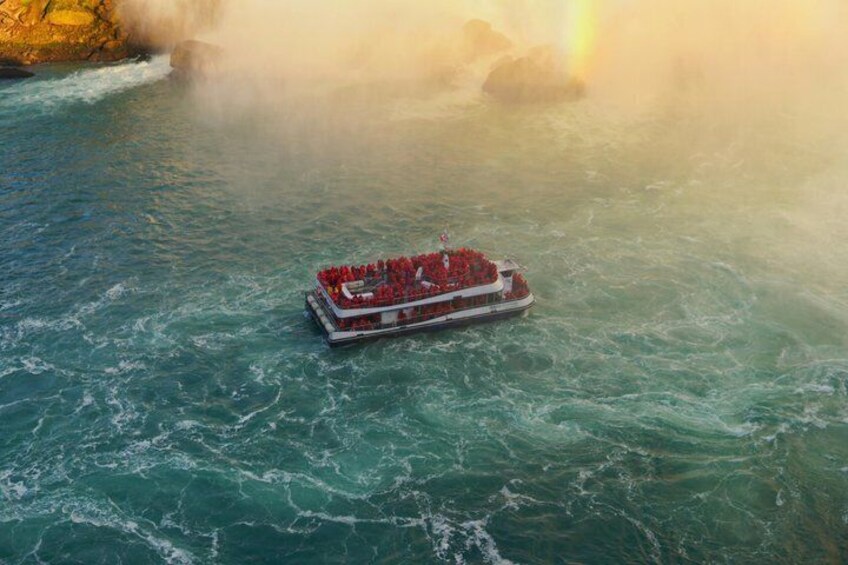 A riverboat with passengers, surrounded by turbulent water and a rocky shoreline. 1